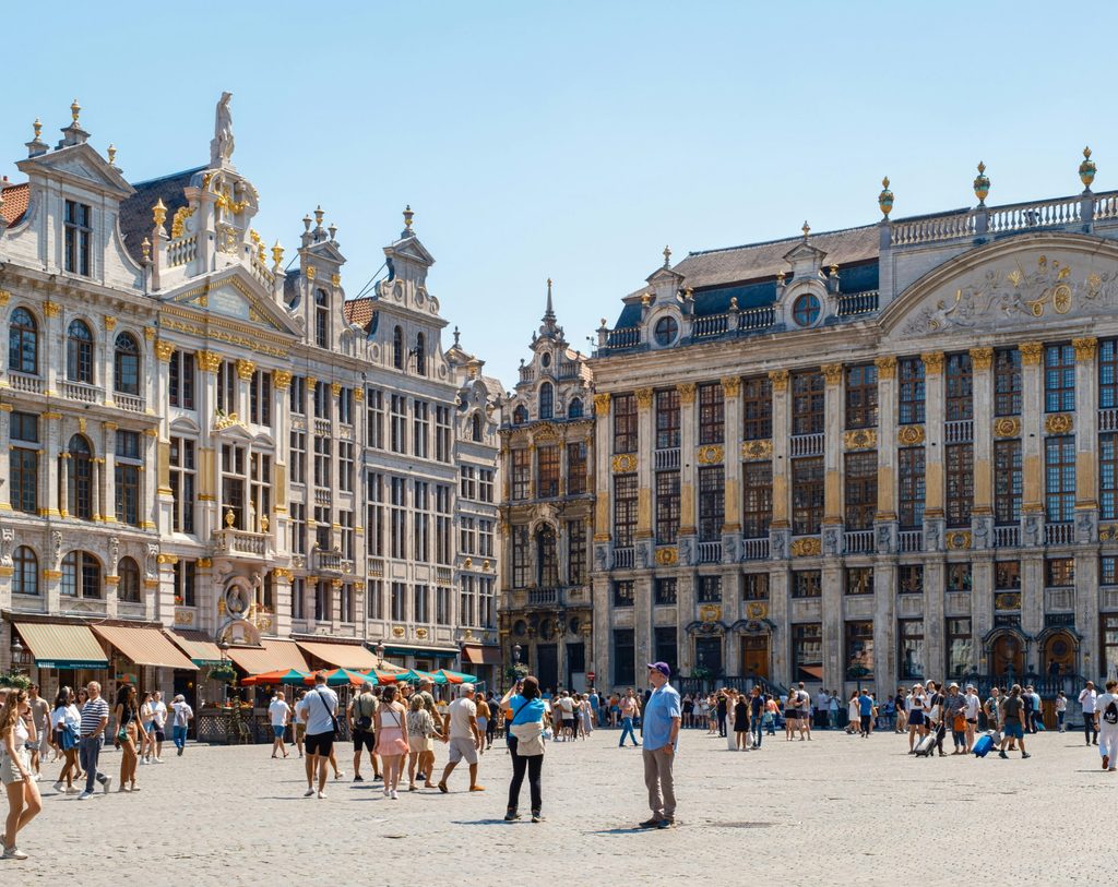 Tourists taking photos of a famous European landmark in a sunny city square